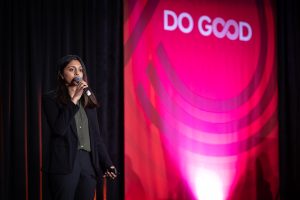 Speaker on stage with a large Do Good sign in the background.