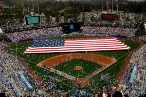 A large American flag unfurled on baseball field
