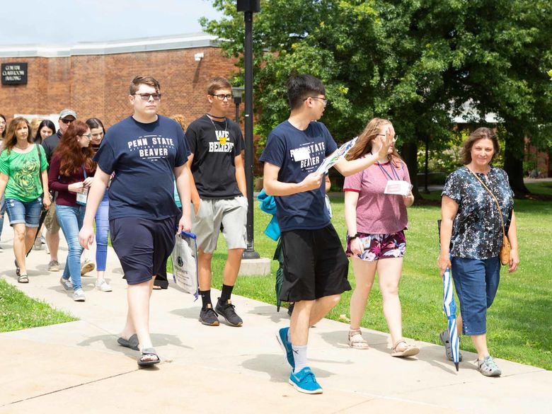 Picture of a tour guide leading and talking to a group of people through campus