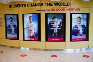 Four large screens embedded into a wall featuring videos of speakers.