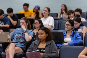 Students listening to a professor in a large lecture hall.