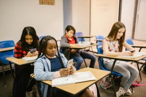 Elementary school students using cell phones at their desks.