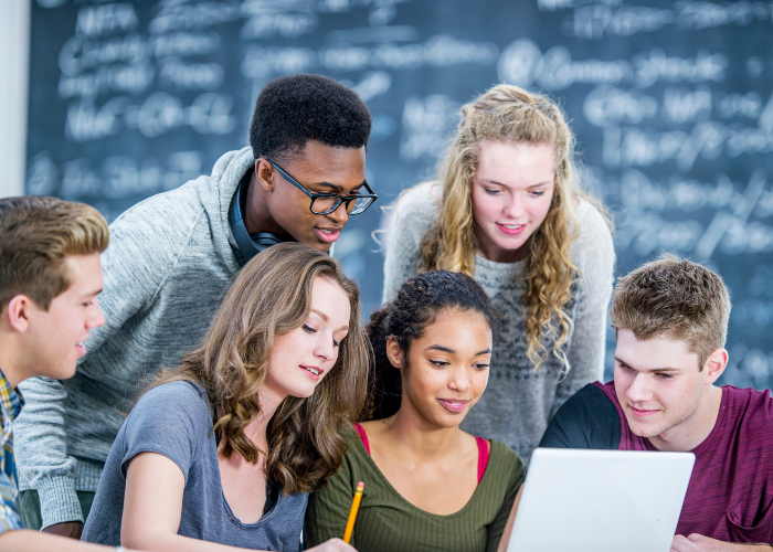 A group of students gather around a laptop